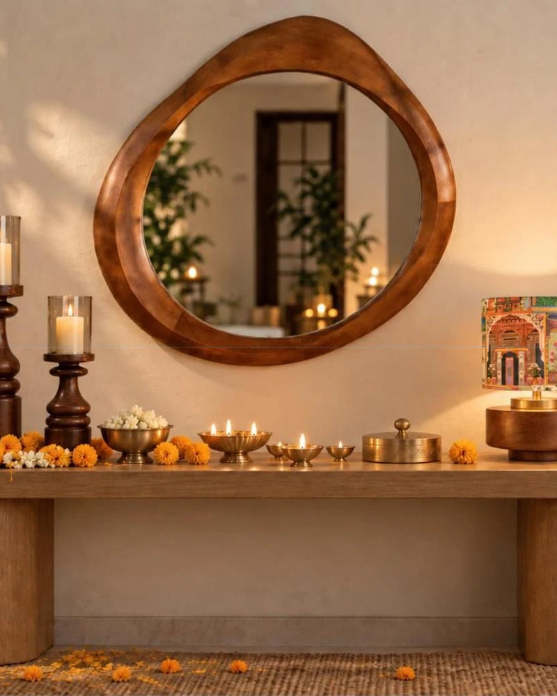 Oval wooden mirror above a console with a table lamp, candles and marigolds