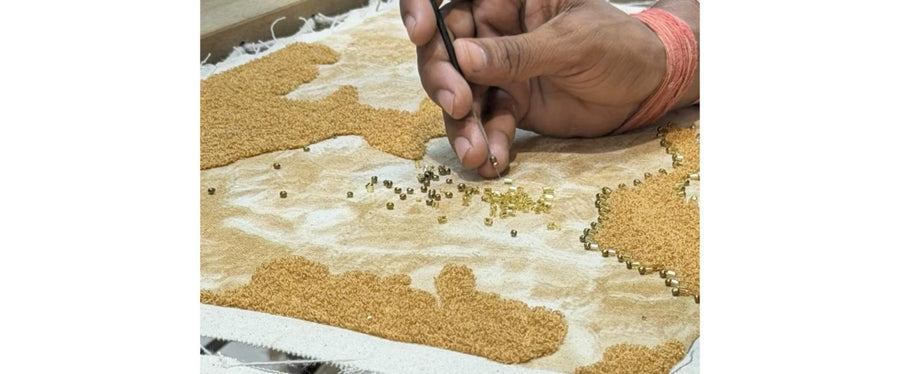 An artisan setting gold beads by hand in our studio