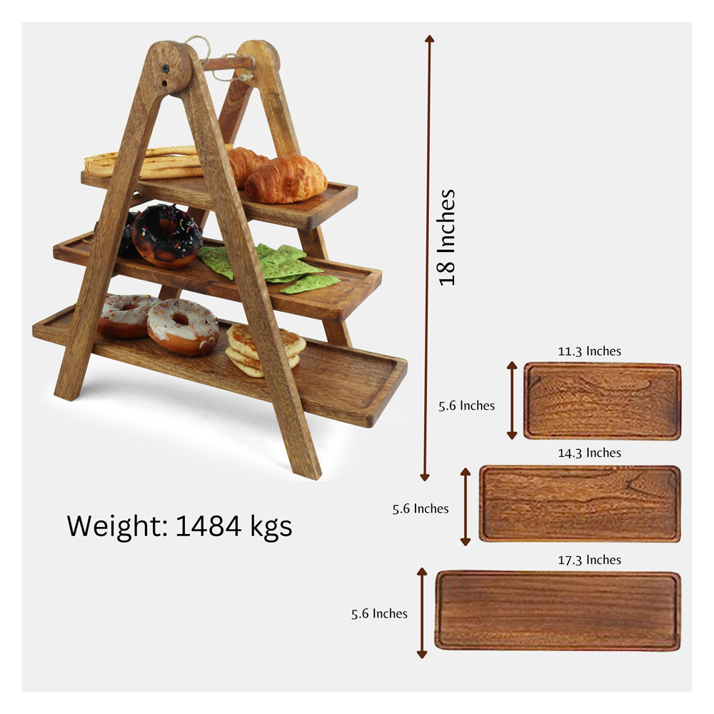 Three-tier wooden serving stand with an A-frame design, displaying assorted pastries, rainbow cake slices, crackers, and leafy greens on a brown tabletop with a neutral gray background