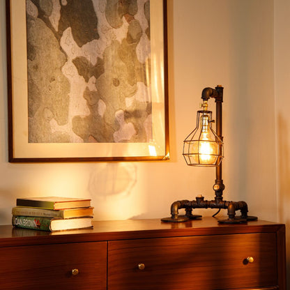 This industrial-style desk lamp features a creative plumbing pipe design and a retro cage bulb holder, blending vintage aesthetics with modern functionality.