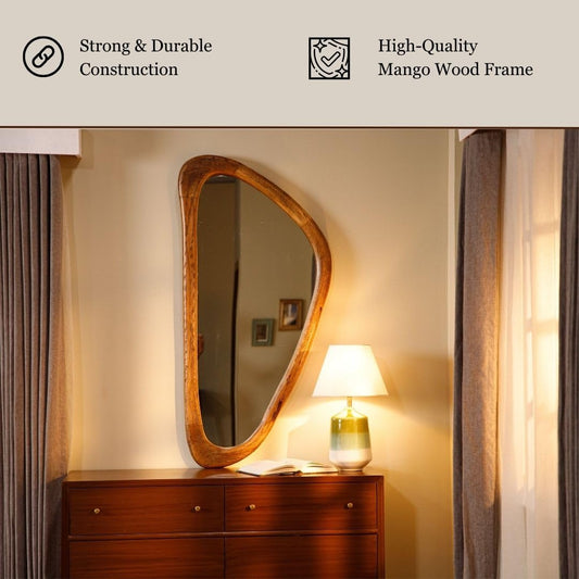 Wooden-framed asymmetrical mirror above a wooden dresser, styled with  lamp