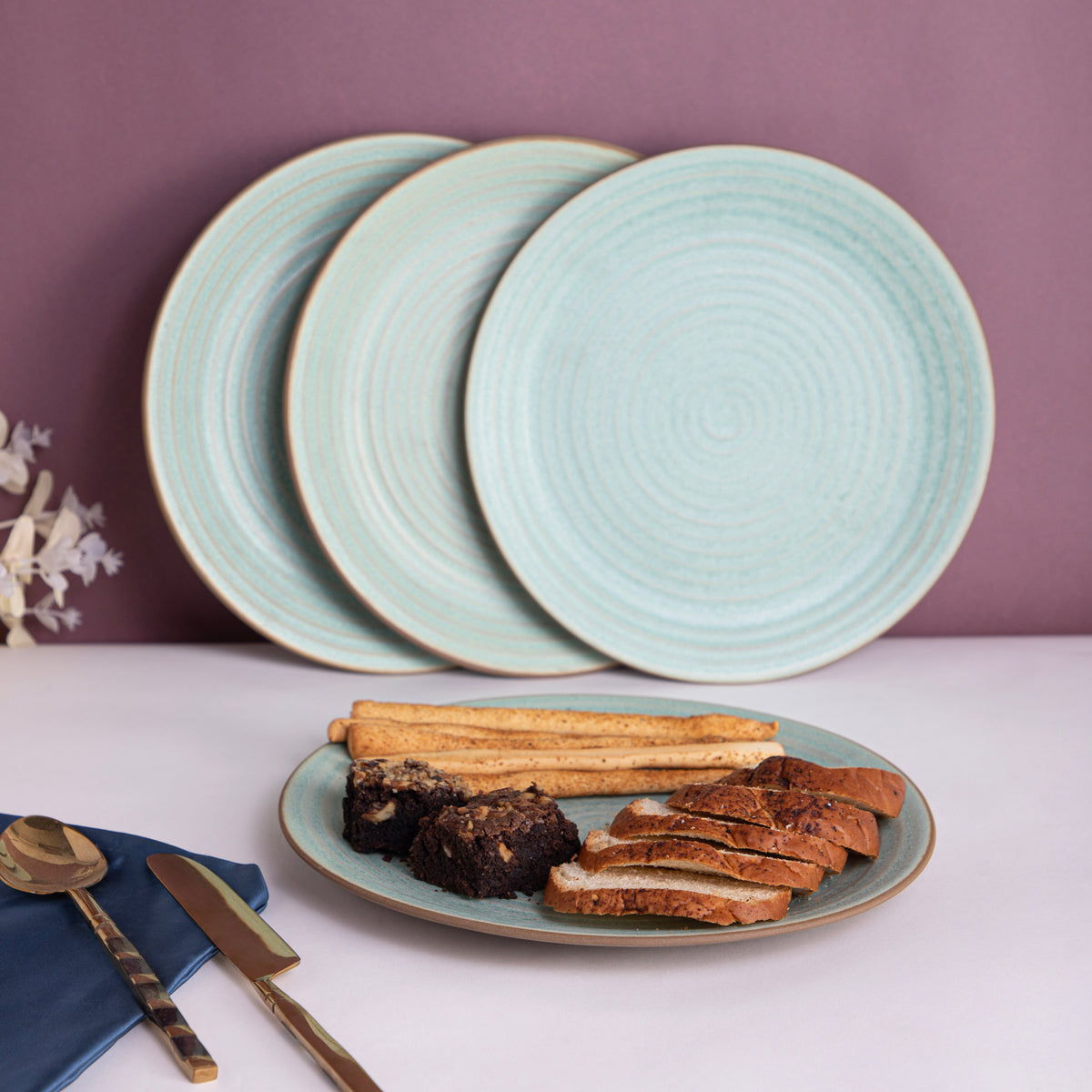 The image shows a set of four light turquoise dinner plates with a circular textured design, measuring 10 inches in diameter, displayed against a purple background