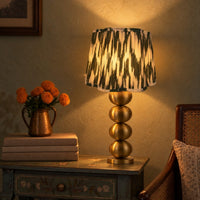 Hara Ikat scalloped lamp shade on the brass column table lamp on a painted side table, warm evening — thumbnail