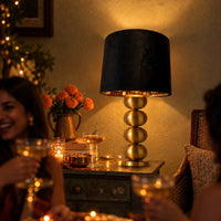 Raat black velvet lamp shade glowing gold on the brass lamp at a party with friends — thumbnail